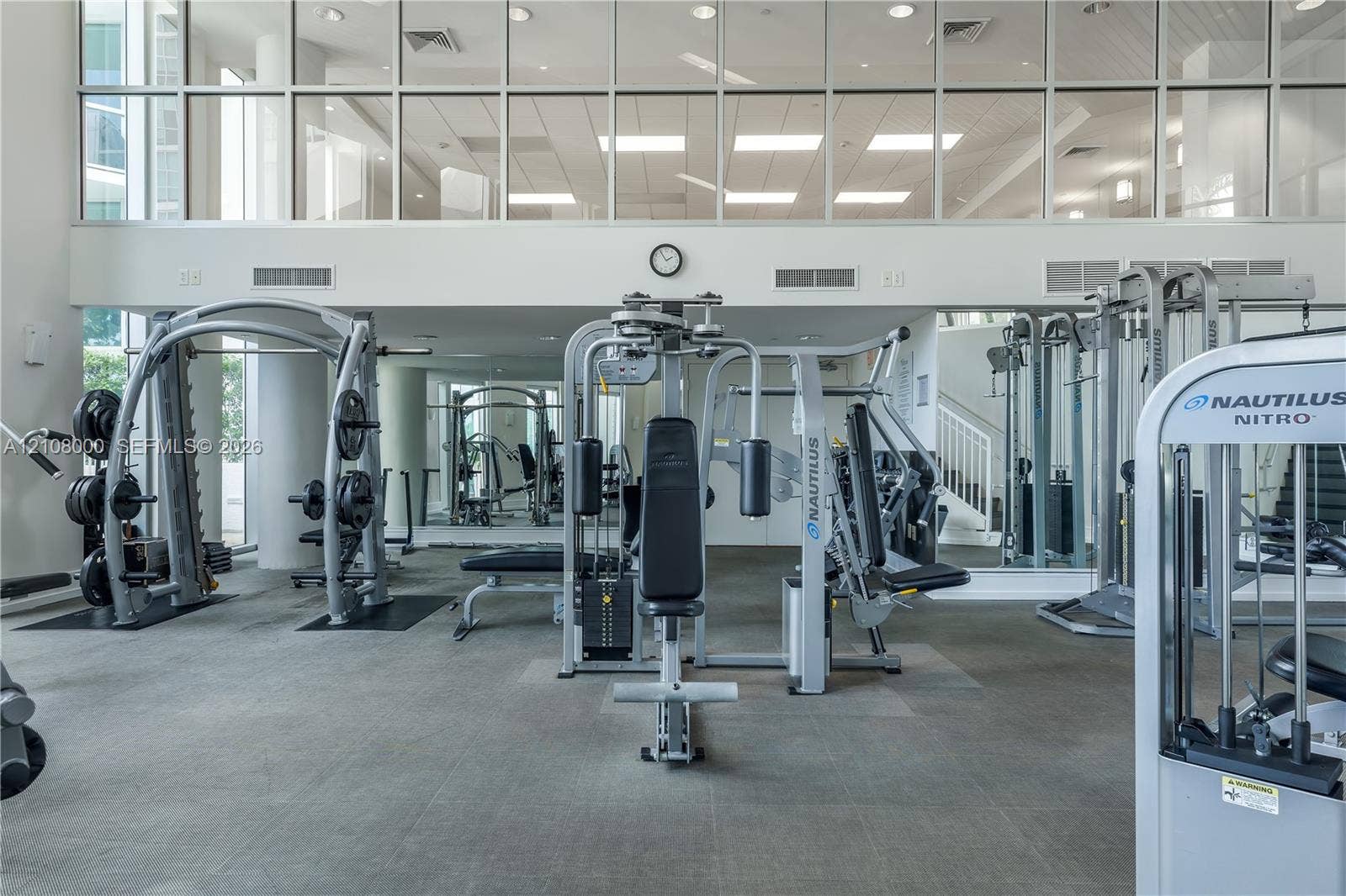 Aventura, FL 33180 Fitness center featuring floor-to-ceiling windows, full-wall mirrors, and high ceilings