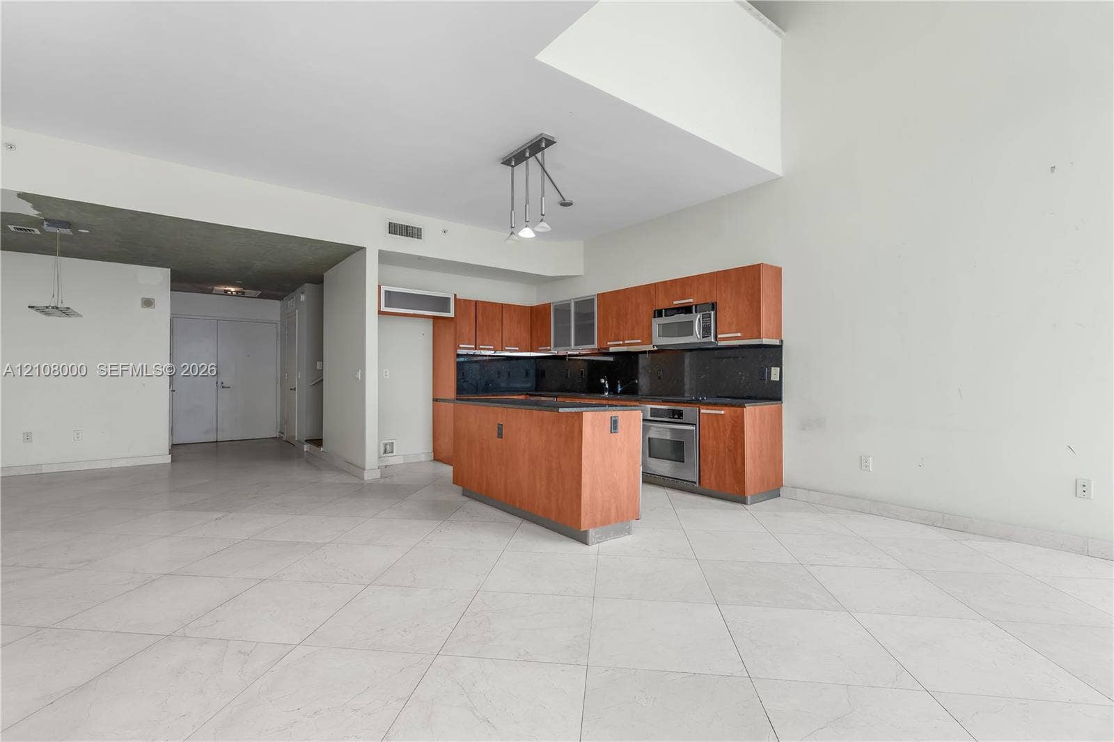 Aventura, FL 33180 Kitchen featuring wood-tone cabinetry, central island, integrated stainless steel appliances, and tile flooring