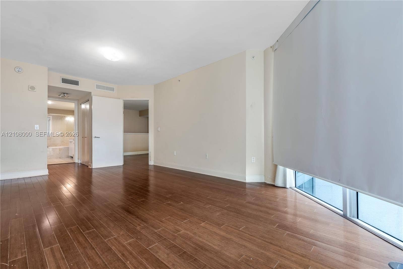 Aventura, FL 33180 Wood-finish flooring, floor-to-ceiling windows with roller shades, and neutral wall tones
