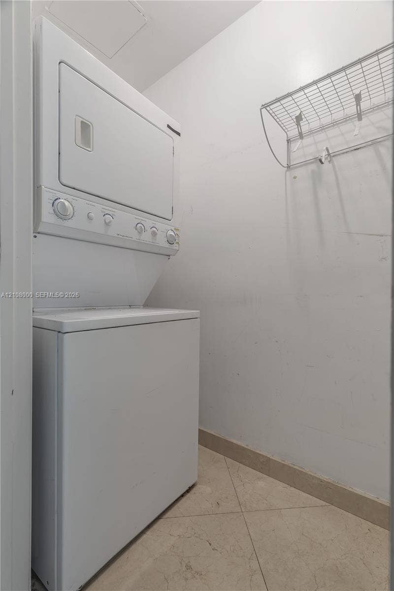 Aventura, FL 33180 Stacked laundry unit with white finish, tile flooring, and integrated metal shelving