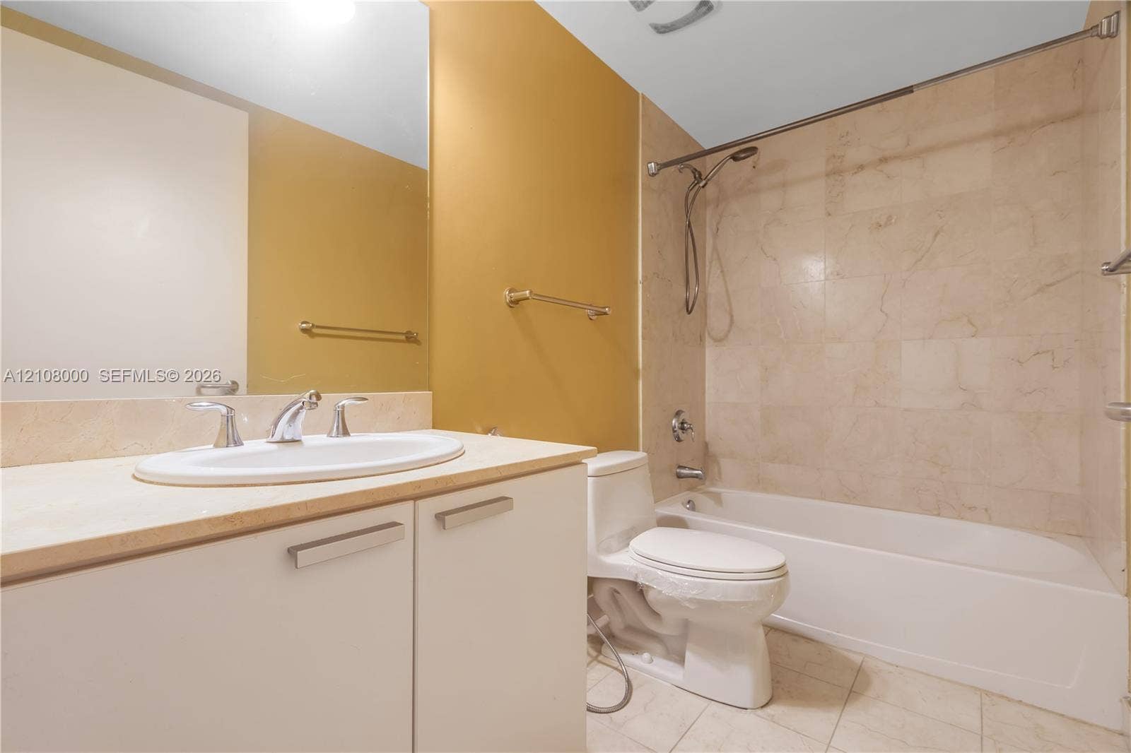 Aventura, FL 33180 Bathroom featuring a vanity with a stone countertop, oval undermount sink, stone tile tub surround, and a wall-to-wall mirror