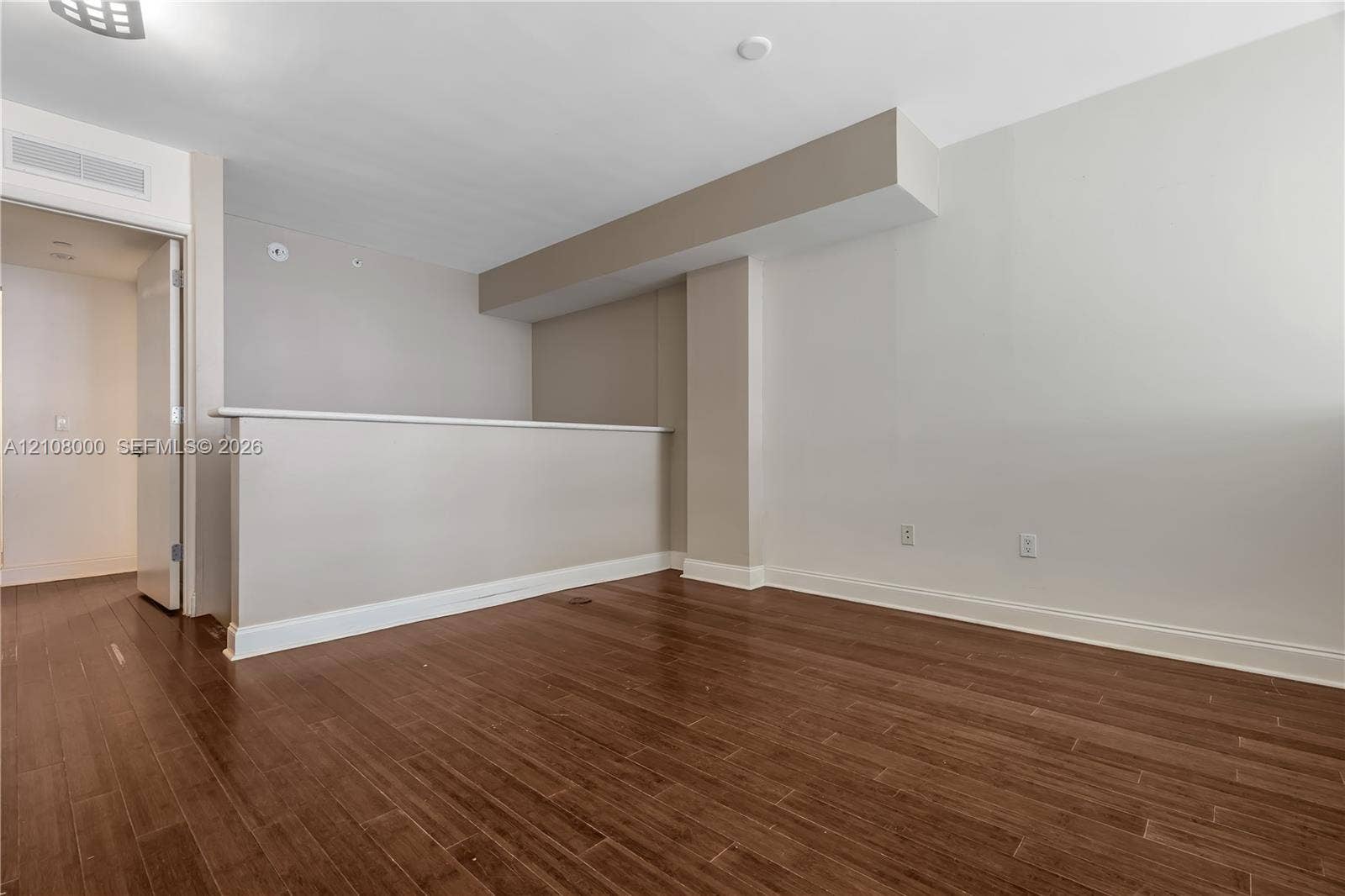 Aventura, FL 33180 Interior space featuring wood-finish flooring, neutral wall tones, a partial height pony wall, and a structural soffit