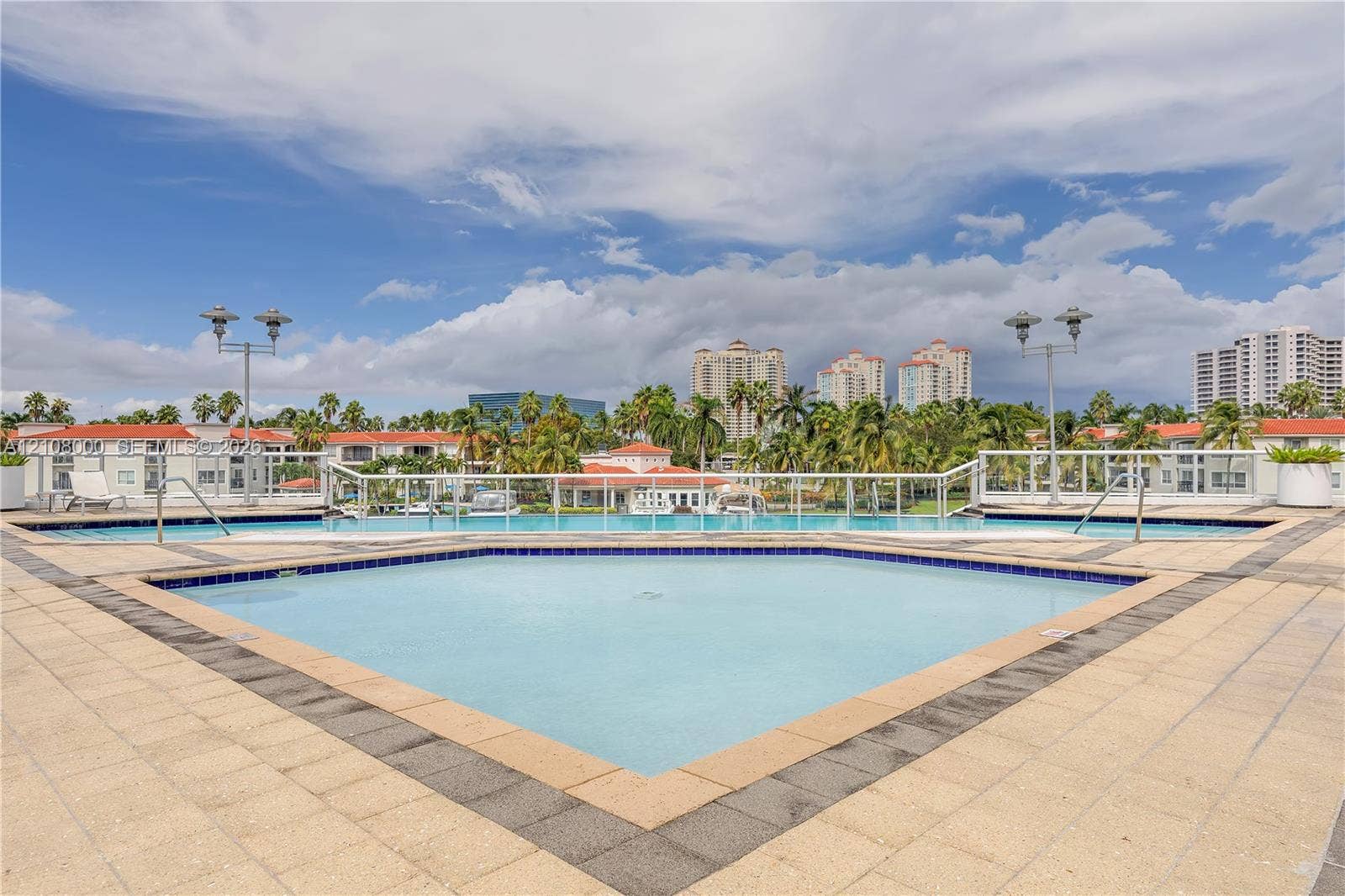 Aventura, FL 33180 Outdoor swimming pool featuring a light-toned tile deck, contrasting border tiles, and a white metal safety railing