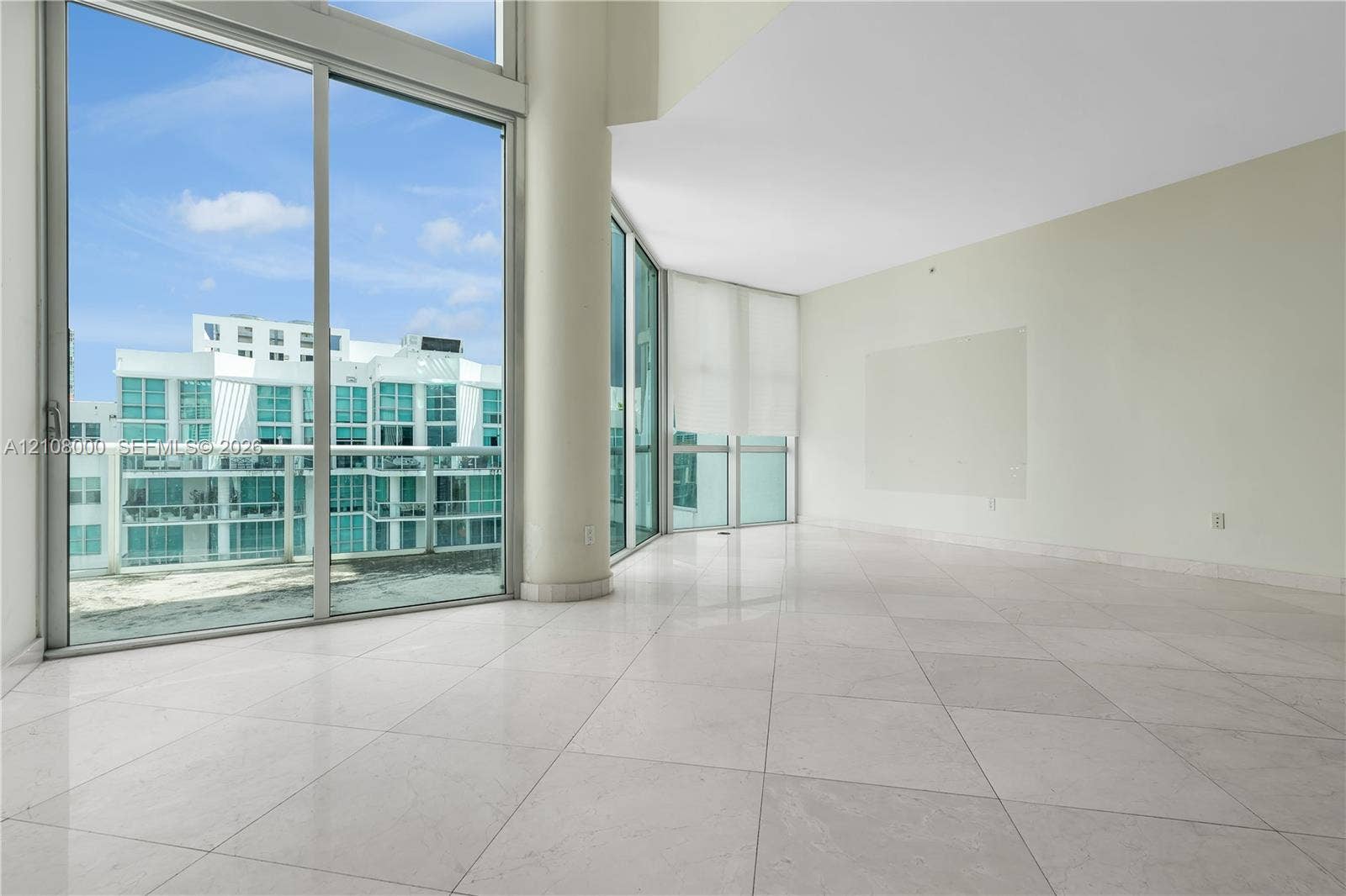 Aventura, FL 33180 Floor-to-ceiling glass windows, expansive stone flooring, structural support column, and glass-paneled exterior balcony