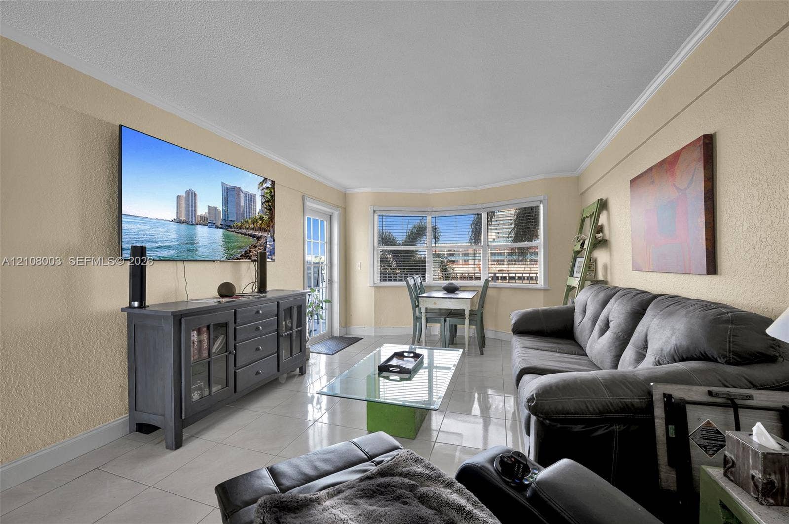 1536 SE 15th Court, #207, Deerfield Beach, FL 33441 Living space featuring large-format tile flooring, crown molding, a multi-pane bay window, and a glass-paned door