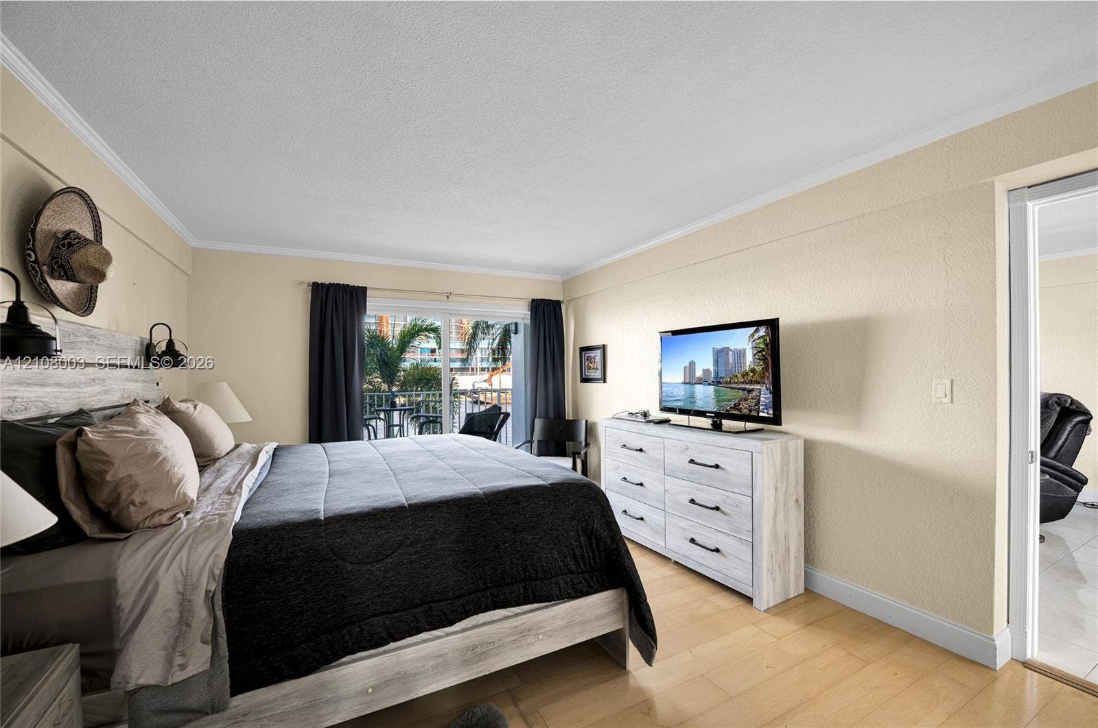 1536 SE 15th Court, #207, Deerfield Beach, FL 33441 Light-filled room featuring wood-finish flooring, sliding glass doors, and dual wall-mounted light fixtures