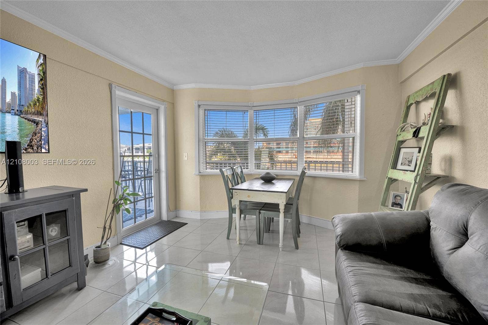 1536 SE 15th Court, #207, Deerfield Beach, FL 33441 Living area featuring large format tile flooring, crown molding, a multi-panel bay window, and a glass-paned exterior door