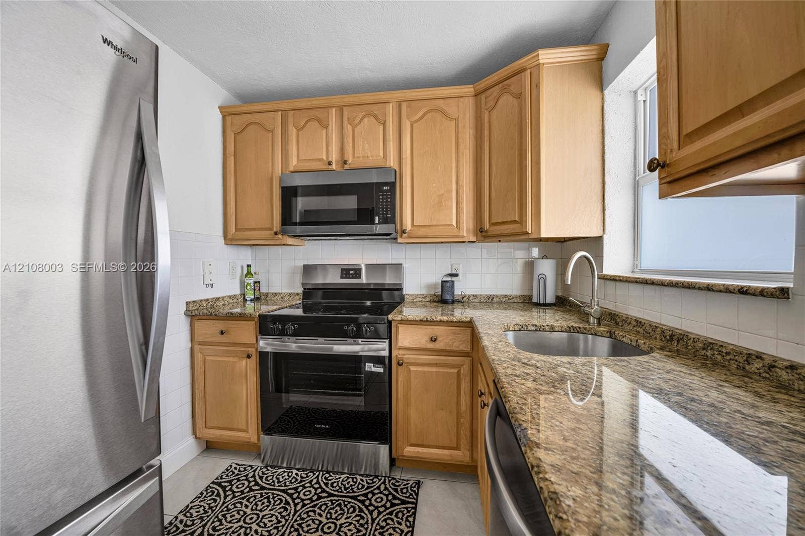 1536 SE 15th Court, #207, Deerfield Beach, FL 33441 Kitchen featuring light-finish cabinetry, stone-style countertops, stainless steel appliances, a white tile backsplash, and an undermount sink