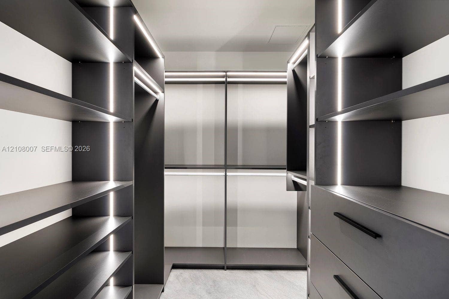 Custom walk-in closet featuring matte charcoal cabinetry, integrated vertical LED accent lighting, open shelving, integrated garment rods, and deep-drawer storage with matte black hardware