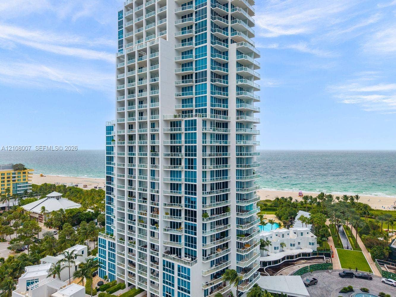 High-rise tower featuring blue-tinted glass curtain walls, white structural accents, and multiple levels of private balconies