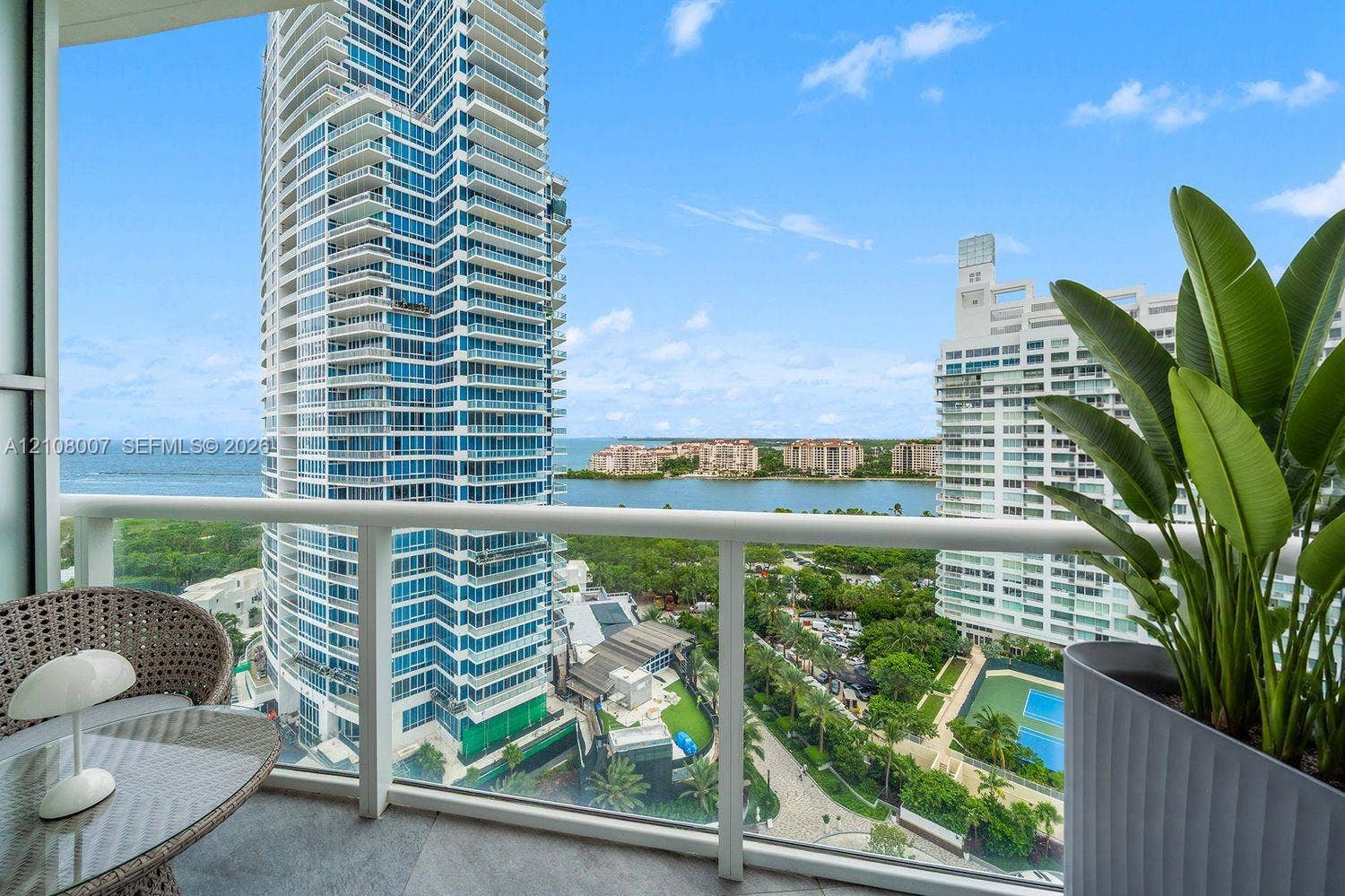 Private covered balcony featuring glass railings and stone flooring, offering expansive water and skyline scenery