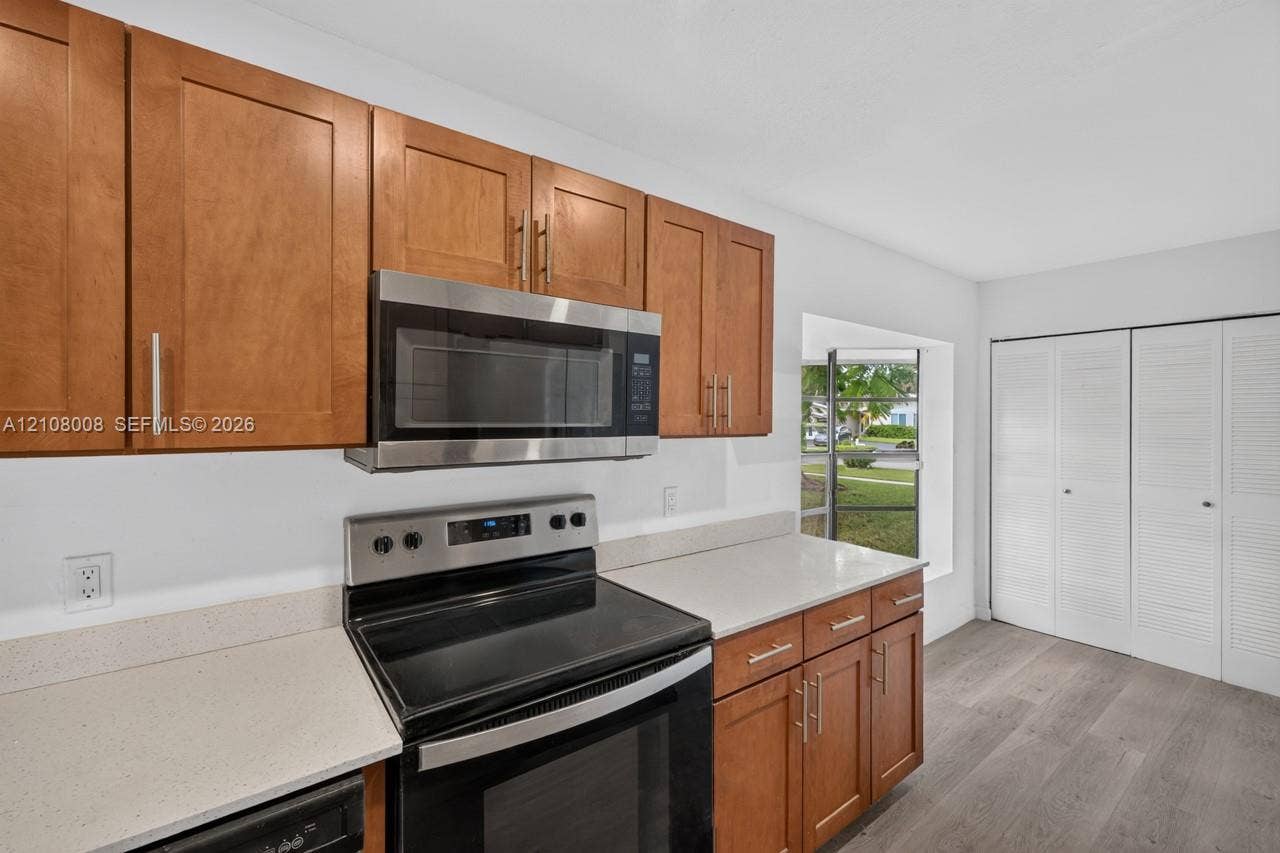 16708 SW 5th Way, Weston, Weston, FL 33326 Kitchen featuring wood cabinetry, stone-finish countertops, stainless steel appliances, a recessed window, and wood-finish flooring
