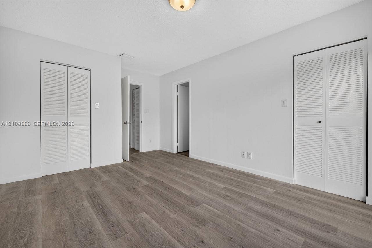 16708 SW 5th Way, Weston, Weston, FL 33326 Wood-finish flooring, two sets of white louvered-door closets, and a flush-mount ceiling light fixture