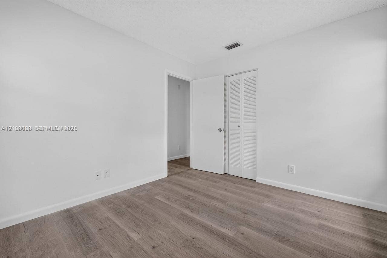 16708 SW 5th Way, Weston, Weston, FL 33326 Room featuring neutral wall paint, wood-finish flooring, and a closet with bifold louvered doors