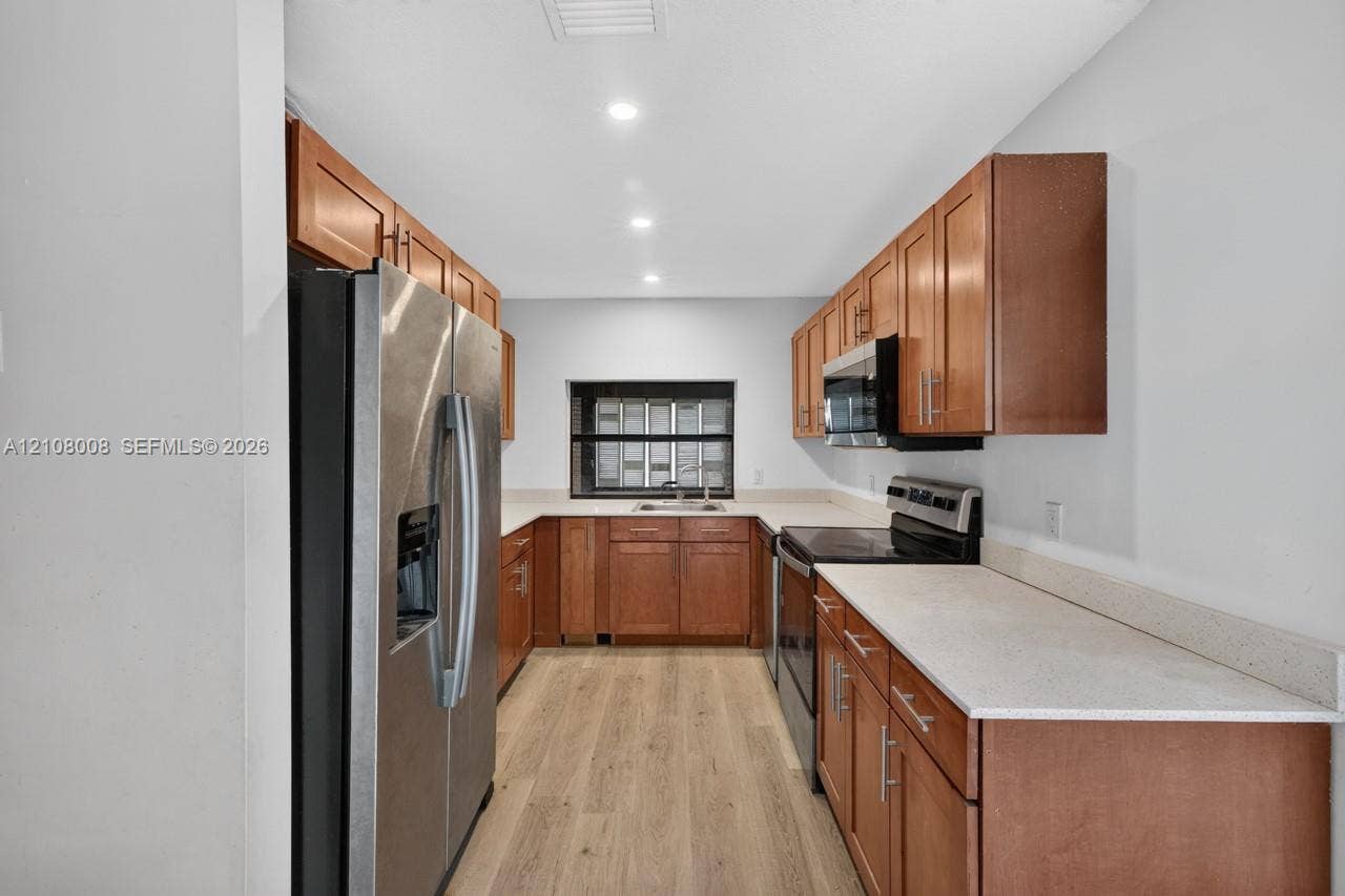 16708 SW 5th Way, Weston, Weston, FL 33326 Kitchen featuring wood cabinetry, stone-finish countertops, stainless steel appliances, and light wood-finish flooring