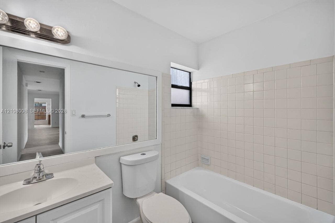 16708 SW 5th Way, Weston, Weston, FL 33326 Full-width vanity with integrated sink, expansive wall-mounted mirror, three-light polished chrome fixture, and tiled tub surround