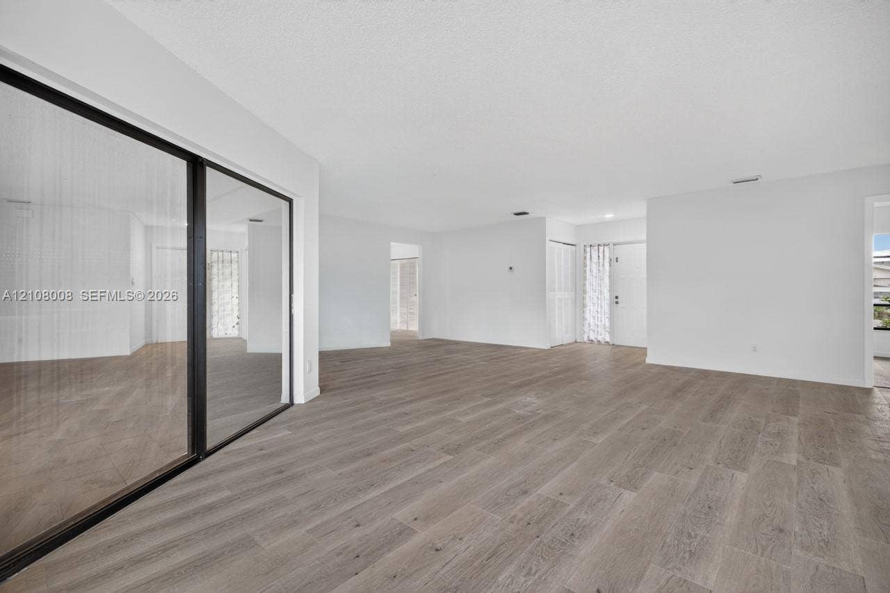 16708 SW 5th Way, Weston, Weston, FL 33326 Interior space featuring wood-finish flooring, floor-to-ceiling sliding glass doors with black frames, and recessed lighting