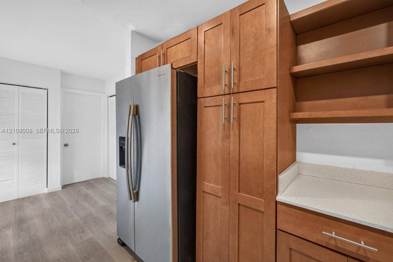 16708 SW 5th Way, Weston, Weston, FL 33326 Stained wood cabinetry, stainless steel refrigerator, solid surface countertops, open shelving, and wood-finish flooring