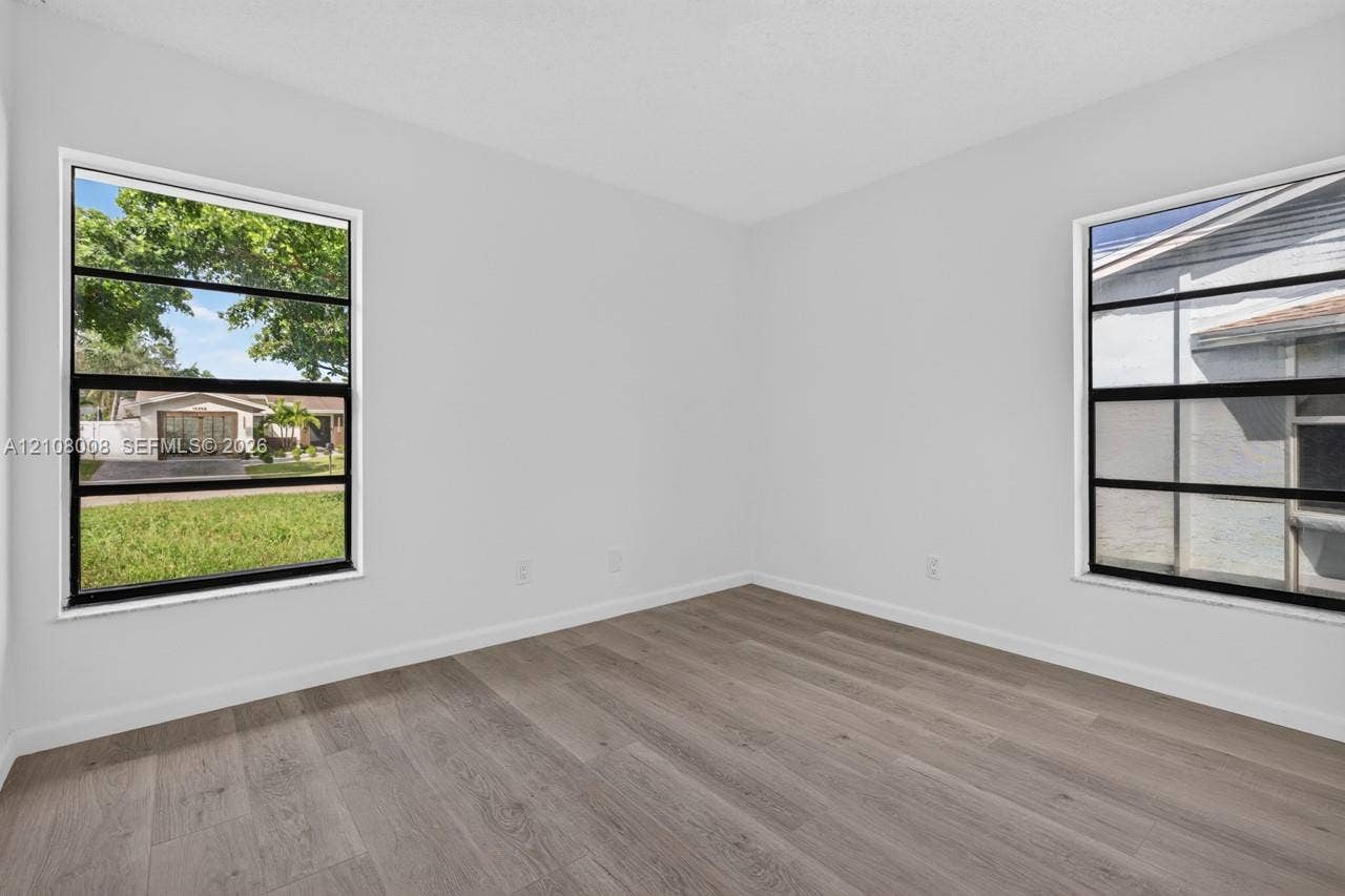 16708 SW 5th Way, Weston, Weston, FL 33326 Neutral-toned interior room featuring wood-finish flooring and dual horizontal sliding windows with black frames