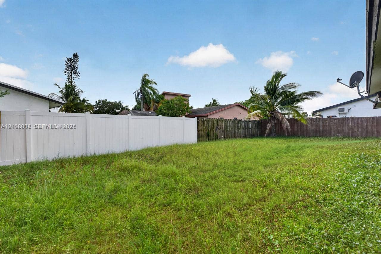 16708 SW 5th Way, Weston, Weston, FL 33326 Open backyard area featuring a white vinyl privacy fence and mature palm trees