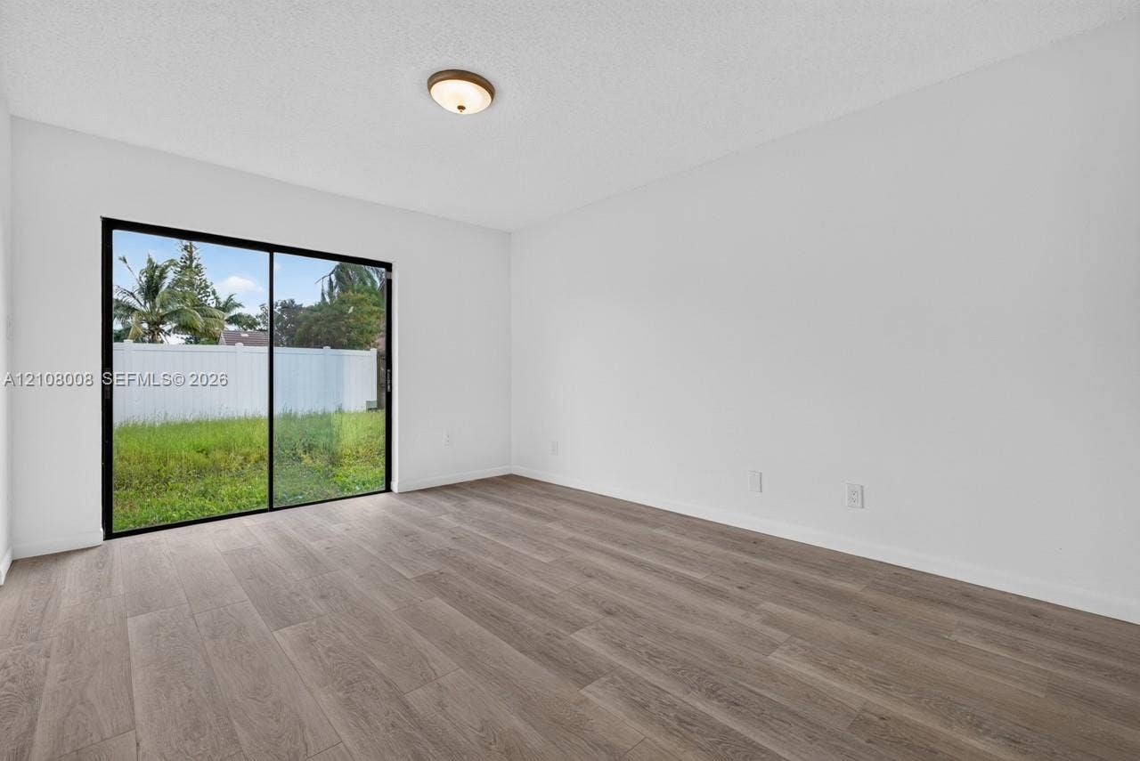 16708 SW 5th Way, Weston, Weston, FL 33326 Interior space featuring wood-finish flooring, white walls, and a glass sliding door
