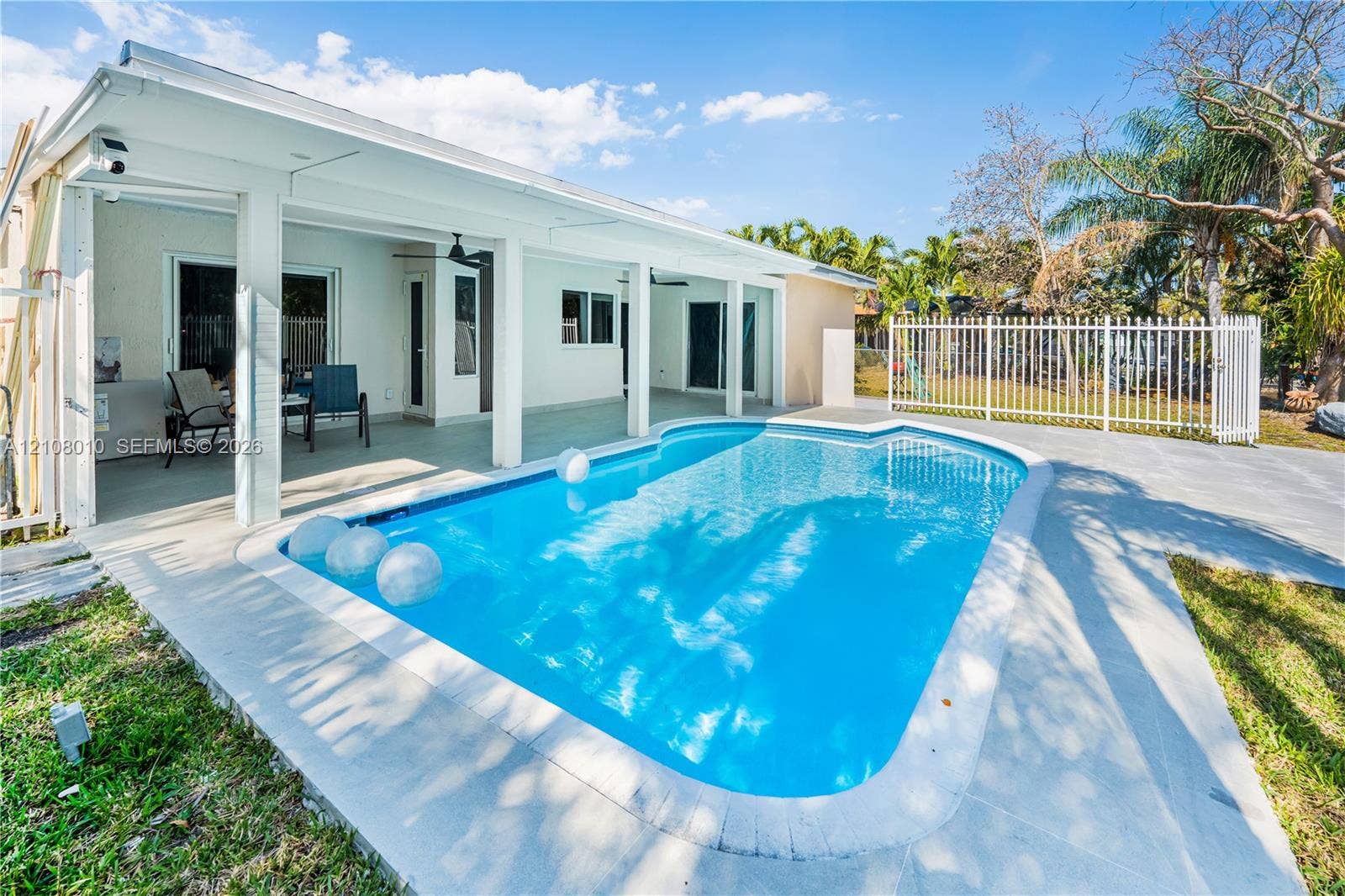 In-ground swimming pool with a concrete pool deck, covered patio, and metal perimeter fencing