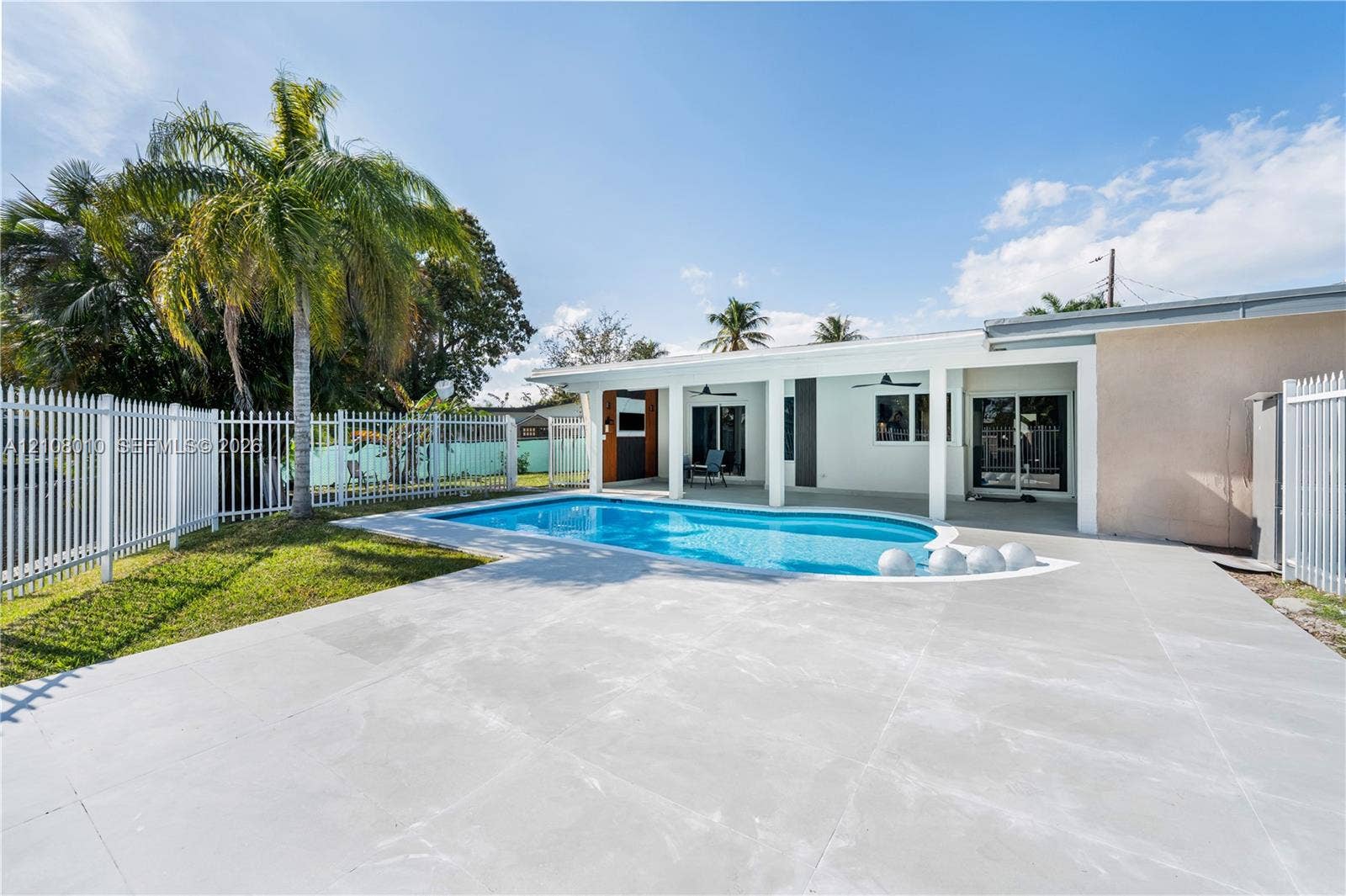 Swimming pool featuring a concrete deck, covered patio with recessed lighting, and white aluminum perimeter fencing