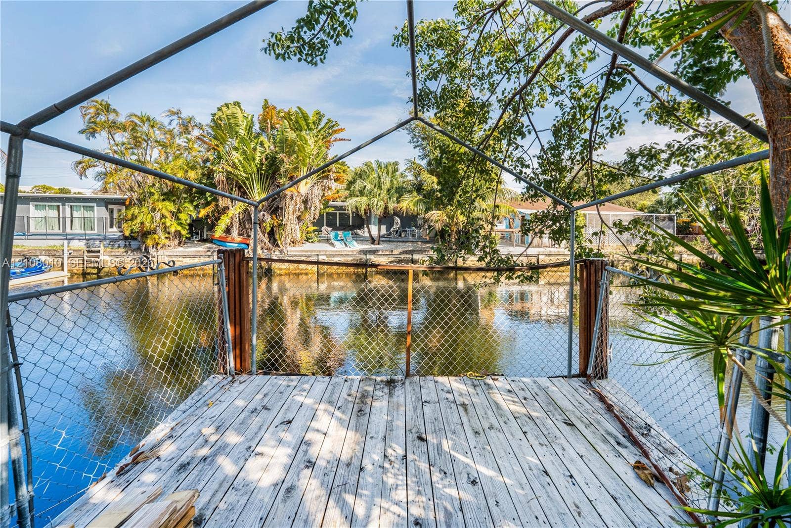 Waterfront dock featuring a wood-plank surface, metal frame enclosure, and perimeter chain-link fencing