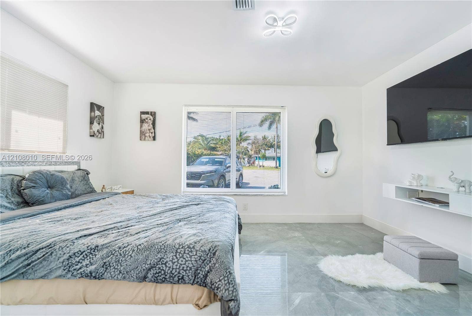 Spacious room featuring polished stone-finish flooring, a contemporary multi-arm flush mount ceiling light, and a white wall-mounted floating media console