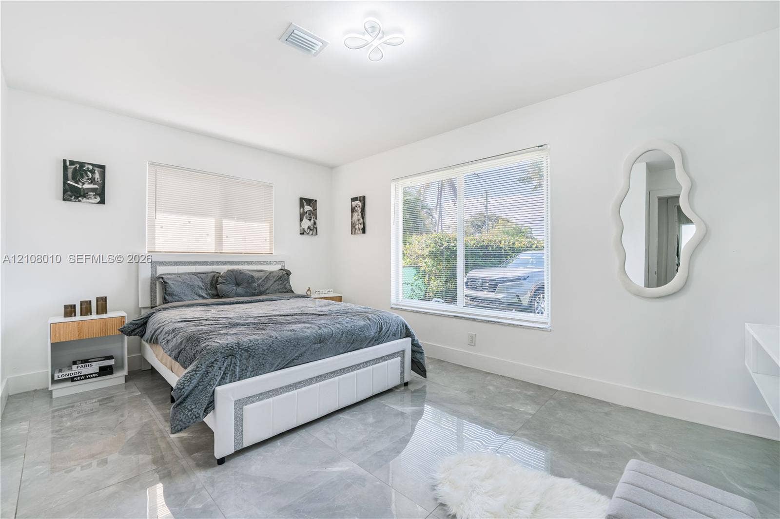 Neutral-toned room featuring large-format polished tile flooring, expansive windows, and a modern geometric flush-mount light fixture