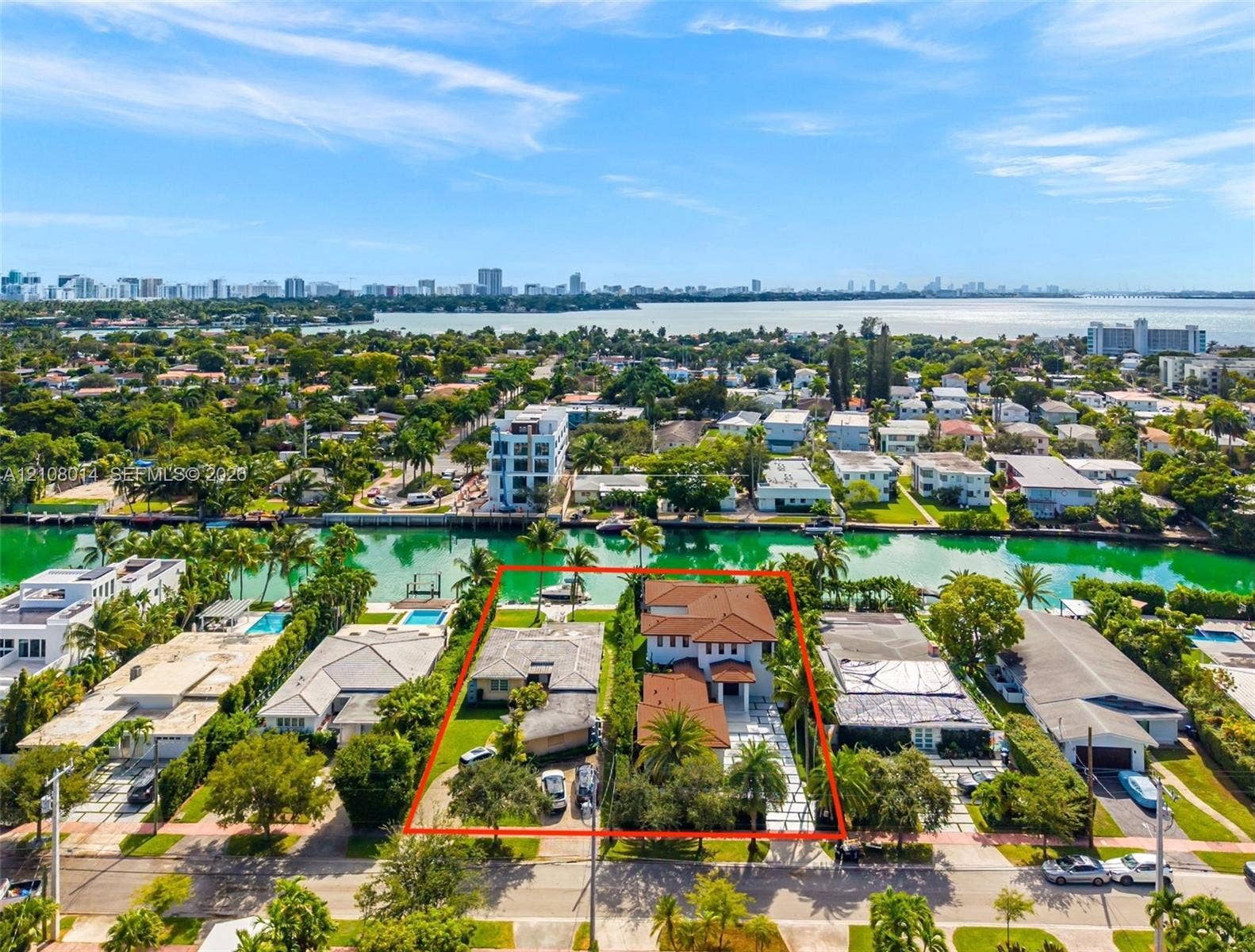 Waterfront property featuring direct canal access, a private boat dock, mature palm landscaping, and tile roofing