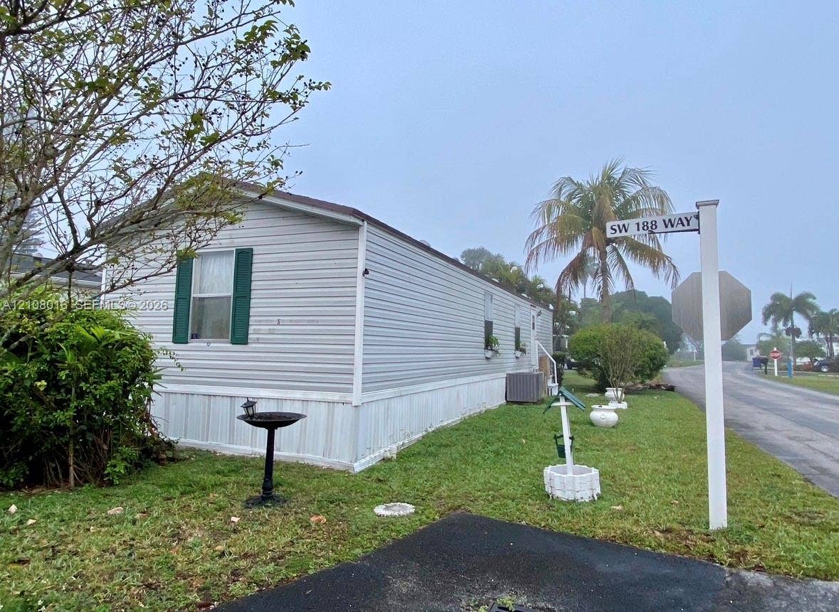 Light-colored horizontal siding, exterior shutters, and grass lawn