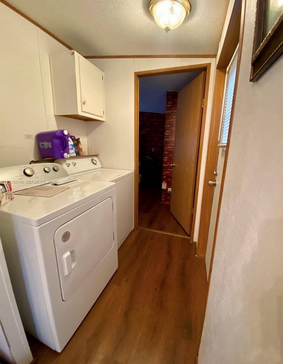 Utility room featuring wood-finish flooring, a wall-mounted storage cabinet, and a dome-style flush mount ceiling light fixture