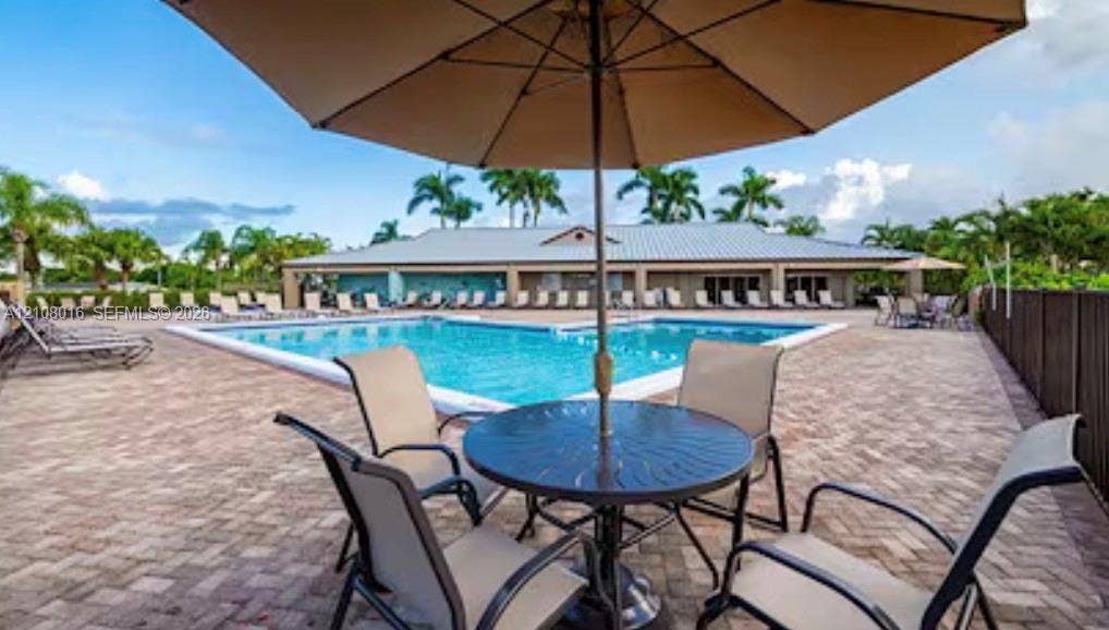 Swimming pool with a brick-paver deck, metal-roof clubhouse, and perimeter fencing
