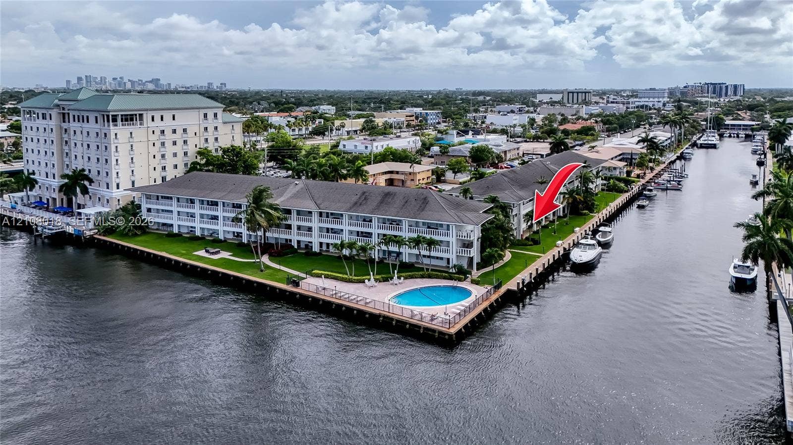 Waterfront residential complex featuring direct canal access, deep-water dockage, a communal swimming pool, and manicured landscaping