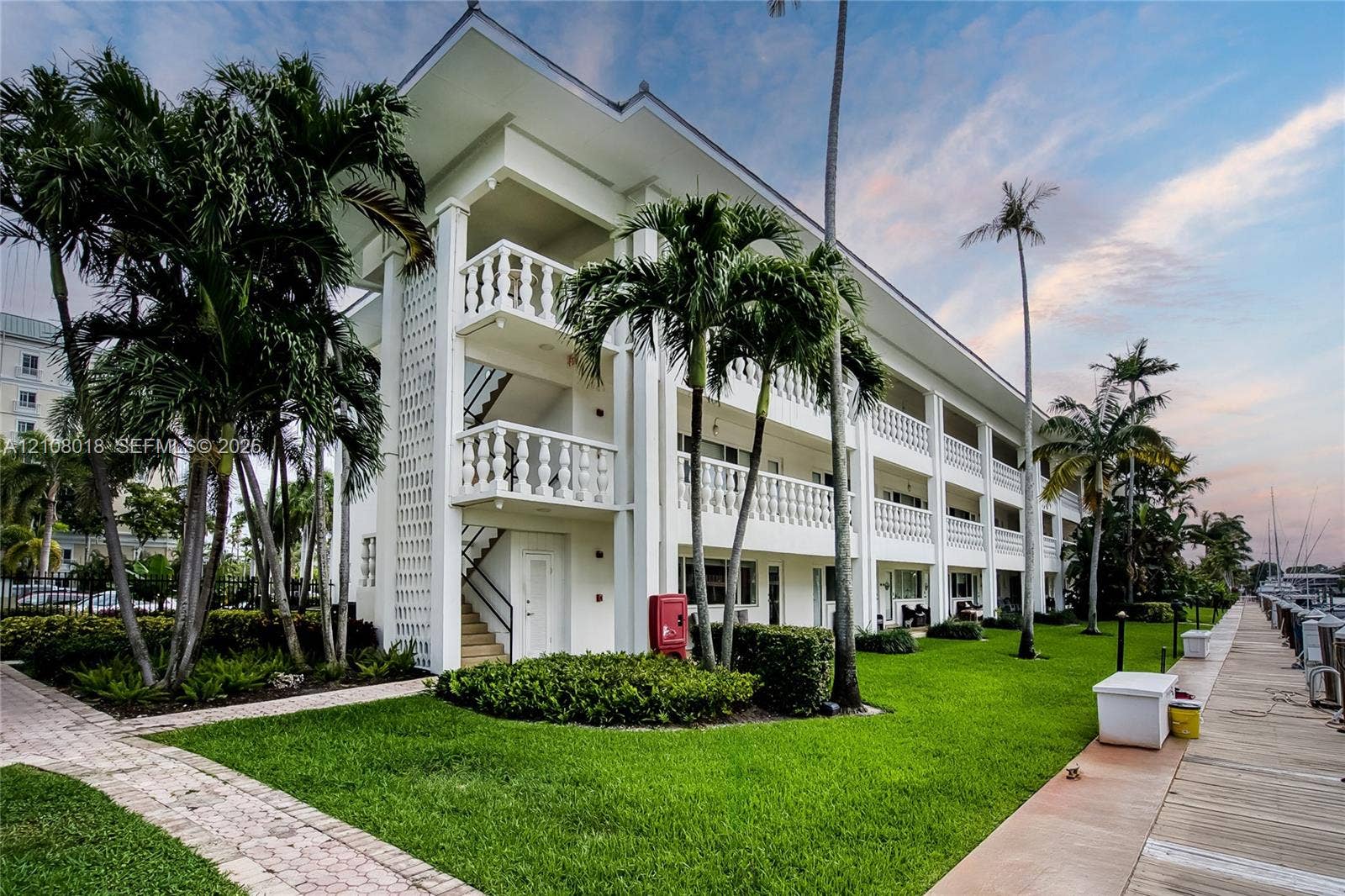 Multi-level exterior featuring white masonry construction, classic balustrade railings, private balconies, and waterfront dock access