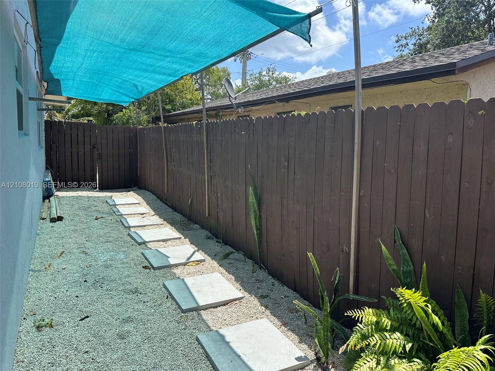 1105 NE 5th Terrace, #1-4, Fort Lauderdale, Fort Lauderdale, FL 33304 Side yard featuring a privacy fence, stone paver walkway, gravel ground cover, and a sun shade canopy