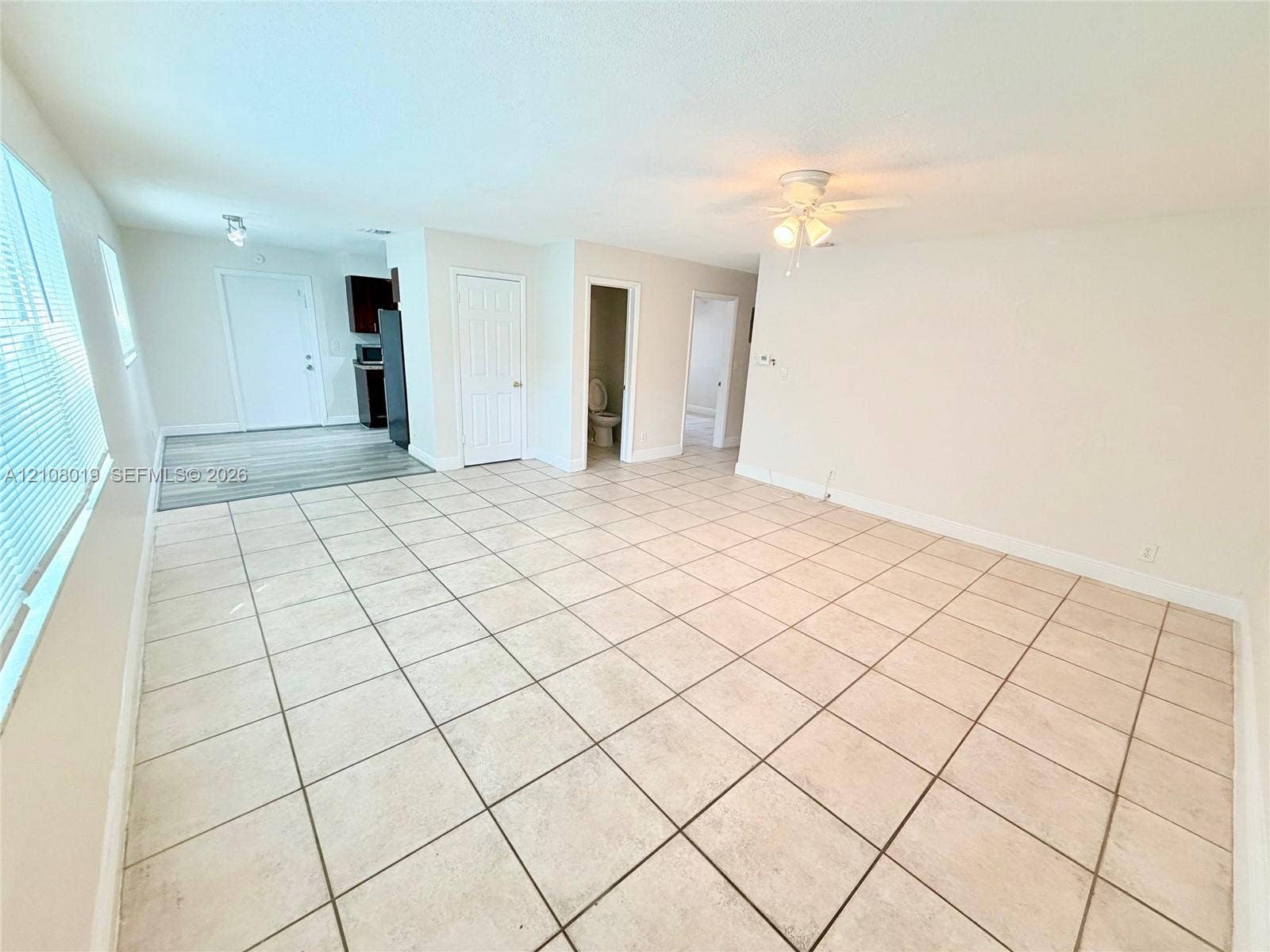 1105 NE 5th Terrace, #1-4, Fort Lauderdale, Fort Lauderdale, FL 33304 Neutral-toned interior featuring large-format square tile flooring, a ceiling-mounted light fixture with fan, and multi-pane horizontal blinds