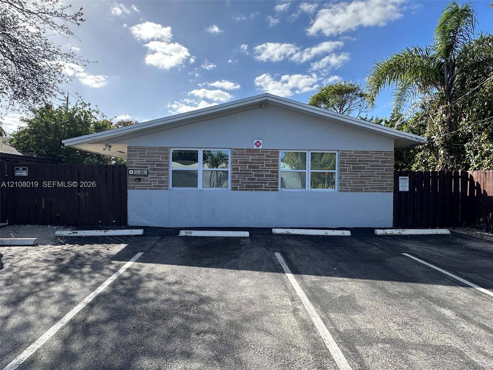 1105 NE 5th Terrace, #1-4, Fort Lauderdale, Fort Lauderdale, FL 33304 Exterior facade featuring stone veneer detailing, wide-eave roofline, and dedicated parking spaces bordered by privacy fencing