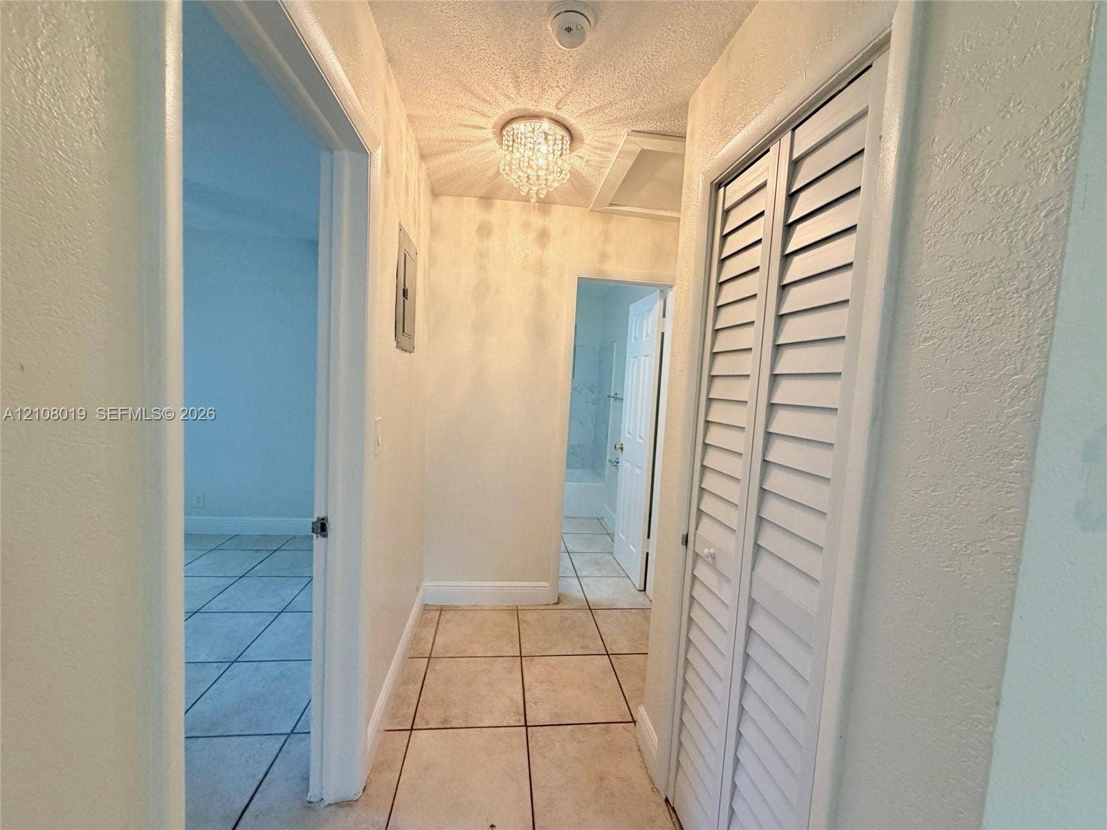 1105 NE 5th Terrace, #1-4, Fort Lauderdale, Fort Lauderdale, FL 33304 Hallway featuring ceramic tile flooring, a crystal-style flush mount light fixture, and white louvered-panel closet doors