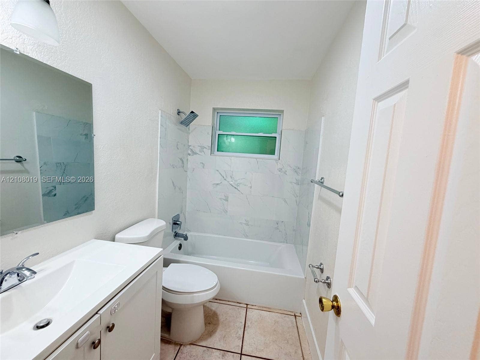 1105 NE 5th Terrace, #1-4, Fort Lauderdale, Fort Lauderdale, FL 33304 Bathroom featuring a vanity with a white integrated sink, polished chrome faucet, rectangular wall-mounted mirror, and a tub-shower combination with light-toned, stone-patterned wall tile