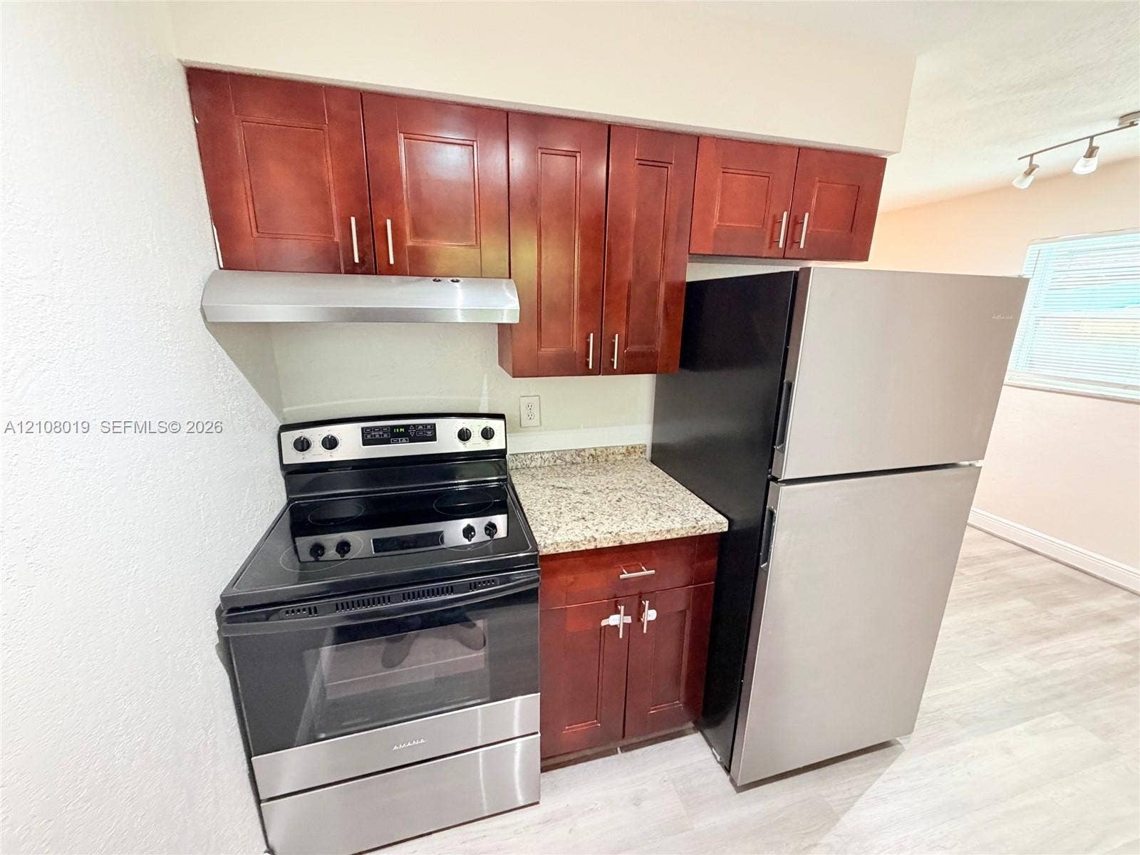 1105 NE 5th Terrace, #1-4, Fort Lauderdale, Fort Lauderdale, FL 33304 Kitchen area featuring wood-finish cabinetry, stone-patterned countertops, a stainless steel electric range, a stainless steel range hood, and a stainless steel refrigerator