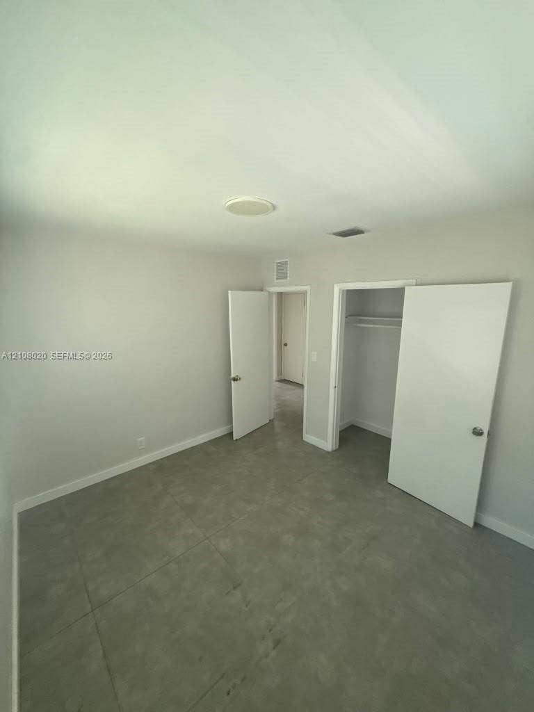 Neutral-toned interior room featuring large-format ceramic tile flooring, a recessed ceiling light, and a built-in closet with integrated shelving