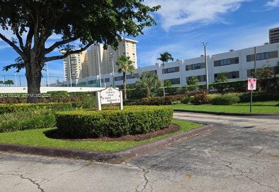 1800 NE 114th Street, #2207, Miami, FL 33181 Landscaped grounds featuring manicured hedging, mature trees, paved driveways, and exterior building facades