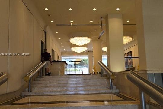 1800 NE 114th Street, #2207, Miami, FL 33181 Entryway featuring stone steps, dual metallic handrails, recessed ceiling lighting, and tiered crystal chandeliers
