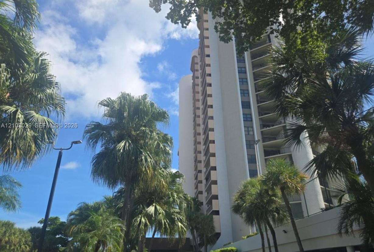 1800 NE 114th Street, #2207, Miami, FL 33181 High-rise residential exterior featuring a multi-story concrete facade with recessed balconies and mature landscaping