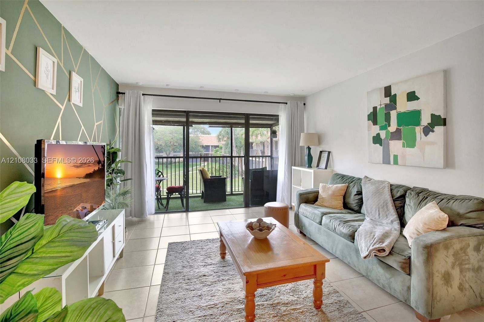 5821 Washington Street, #30, Hollywood, Hollywood, FL 33023 Living area featuring large-format tile flooring, a geometric-patterned accent wall, and sliding glass doors leading to a screened balcony