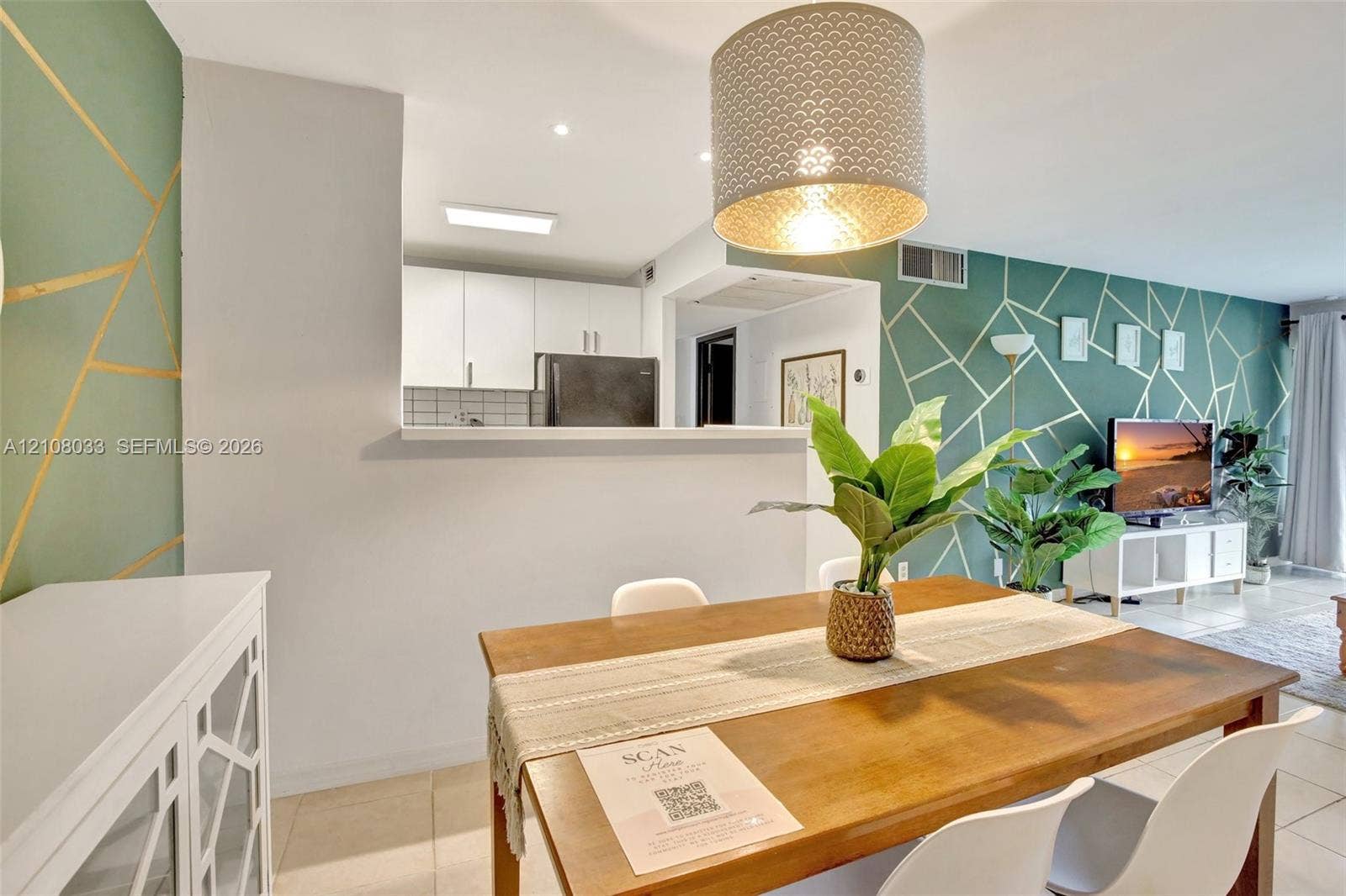 5821 Washington Street, #30, Hollywood, Hollywood, FL 33023 Open-concept interior featuring geometric accent walls, pass-through kitchen opening, drum pendant lighting, and large-format tile flooring