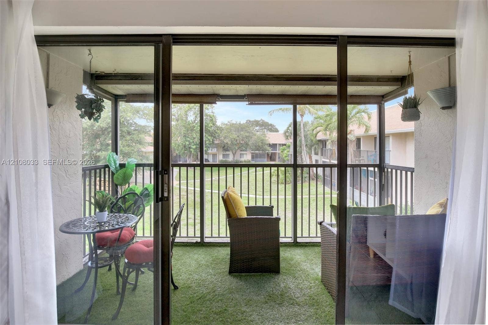 5821 Washington Street, #30, Hollywood, Hollywood, FL 33023 Screened-in balcony featuring an overhead cover, synthetic turf flooring, and metal railing