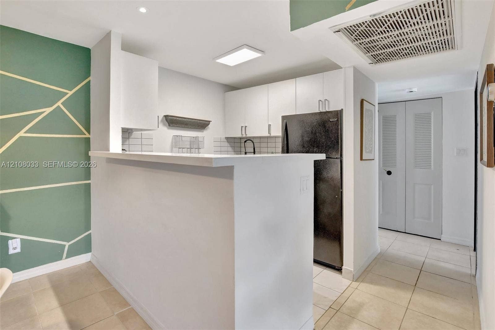5821 Washington Street, #30, Hollywood, Hollywood, FL 33023 Kitchen featuring a breakfast bar, white cabinetry, tile backsplash, black refrigerator, and tile flooring